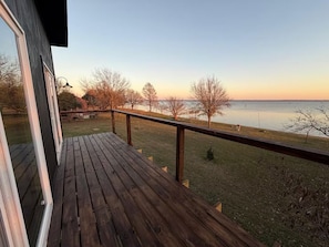 Une terrasse en bois dotée d’une rambarde, qui offre une vue sur une étendue d’eau.