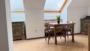 Een kamer met dakraam, een eettafel met stoelen, een potplant en een groene kast.