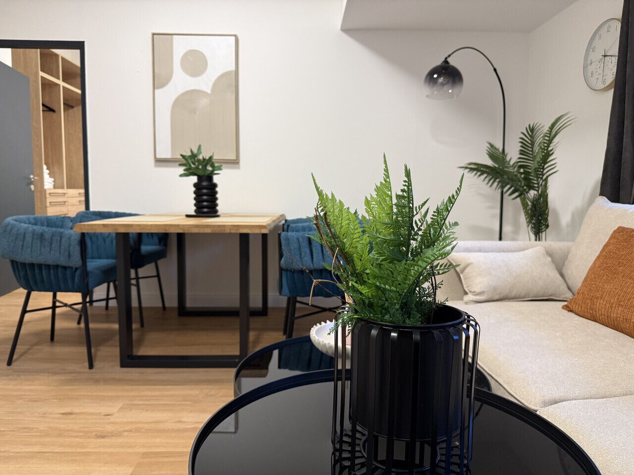 Een moderne woonkamer met een eethoek, een bank, een salontafel en een potplant.