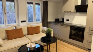 Una sala de estar moderna con un sofá, una mesita redonda y una zona de cocina con estufa y alacenas.