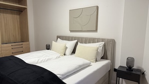 Un dormitorio con cama, mesitas de noche, armario y una obra de arte colgada en la pared.