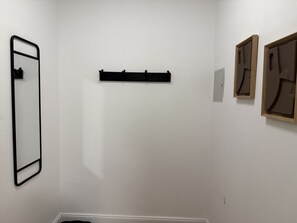 Ein minimalistisch eingerichteter Raum mit schwarzem Metallgestell, einer Holzablage und zwei gerahmten Kunstwerken an der Wand.