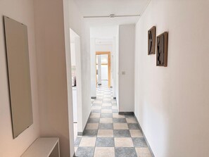Un pasillo con piso a cuadros, paredes blancas y obras de arte enmarcadas.