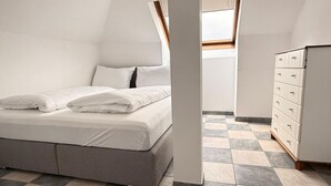Une chambre à coucher avec un lit, une commode et une lucarne.