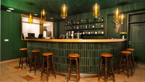 A bar area with a green tiled wall, wooden stools, and hanging light fixtures. - Faraway Homes Studio Semmering #301 (Spital am Semmering)