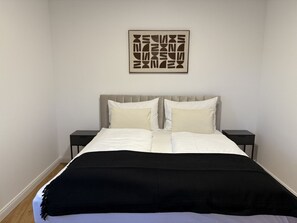 Ein Bett mit schwarz-weiß gestreifter Bettdecke, zwei Nachttische und ein Wandbild darüber.