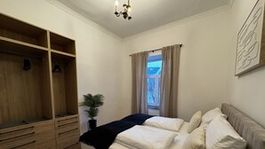 Een slaapkamer met een bed, een houten garderobe, een kamerplant en een raam met gordijnen.