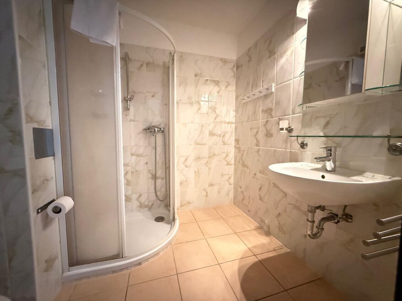 Un baño con ducha de vidrio, un lavabo blanco y un espejo encima.
