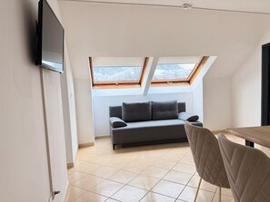 Ein modernes Wohnzimmer mit einer Couch, einem an der Wand befestigten Fernseher und einem Oberlicht.