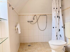 Ein Badezimmer mit Dusche, Toilette und Duschkabine.