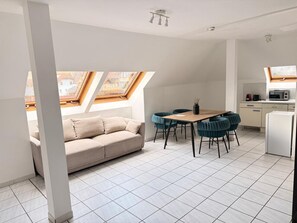 En modern lägenhet med matplats, ett litet kök och en soffa.