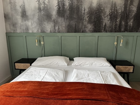 Una cama con sábanas blancas, cabecera verde y dos mesitas de noche con cestas tejidas.. Faraway Homes Studio Semmering #105