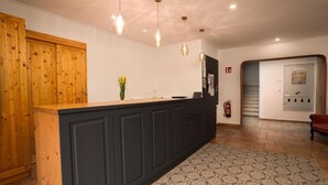A reception area with a wooden counter, dark cabinets, hanging pendant lights, a patterned rug, and a fire extinguisher. - Faraway Homes Studio Semmering #105 (Spital am Semmering)