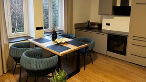 Een moderne keuken met een eethoek, grote ramen en uitzicht op bomen.