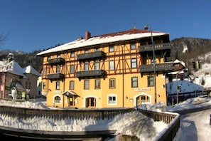 En byggnad med flera våningar i traditionell arkitektonisk stil, med en balkong på andra våningen och ett snötäckt tak.