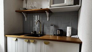 Een kleine keuken met een houten aanrecht, een spoelbak, een magnetron en een handdoekdispenser.