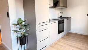 Uma cozinha moderna com armários brancos, forno embutido e bancada preta.