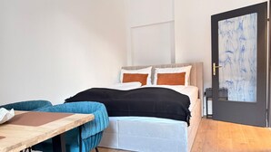 Quarto com cama, mesa de cabeceira e porta com um quadro.