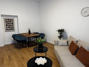 A modern living room with a sofa, a dining table with chairs, a coffee table, and a wall clock. - Faraway Homes Studio Semmering #205 (Spital am Semmering)