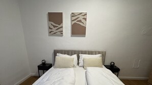 Un letto matrimoniale con biancheria da letto bianca, due comodini e due opere d'arte astratte appese alle pareti.