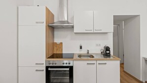 A compact kitchen with a built-in oven, a stainless steel range, a sink, and a coffee maker. - FarawayHomes Studio Vienna #3 (Vienna)