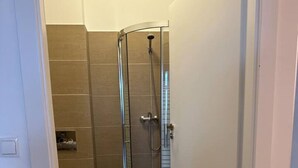 A bathroom with a glass-enclosed shower, a toilet, and a small rug on the floor. - FarawayHomes Studio Vienna #3 (Vienna)
