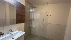 A bathroom with a sink, mirror, shower, and tiled walls. - FarawayHomes Aparthotel Kremsmünster #22 (Kremsmünster)