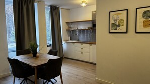 Une cuisine moderne avec des meubles blancs, une table à manger en bois et une plante en pot.