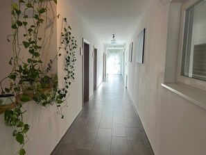 A hallway with a tiled floor, white walls, and a hanging plant.