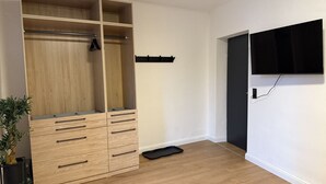 Een kamer met een houten garderobe, een zwarte dienblad, een wandtv en een potplant.