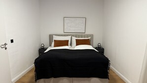 Een slaapkamer met een bed, nachtkastjes, een kunstwerk aan de wand en een houten vloer.