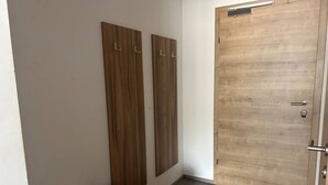 A room with a wooden door, a bench, and two vertical wooden panels. - FarawayHomes Aparthotel Kremsmünster #25 (Kremsmünster)