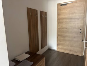A room with a wooden door, a bench, and two vertical wooden panels.