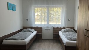 A room with two single beds, a small table, and a window with curtains. - FarawayHomes Aparthotel Kremsmünster #2 (Kremsmünster)