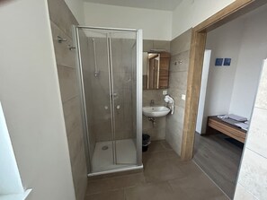 Une salle de bain avec une douche à parois de verre, un lavabo et un banc en bois.