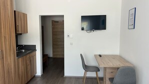 Et moderne køkken med træskabe, en indbygget vask og et fladskærms TV monteret på væggen.