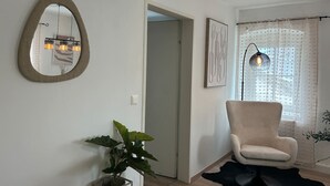 Ein Zimmer mit Spiegel, Stuhl, Pflanze und Stehlampe.