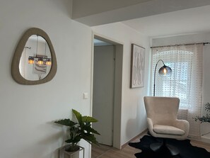 Een woonkamer met een grote spiegel, een stoel, een potplant en een vloerlamp.
