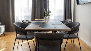 Un'area pranzo moderna con un tavolo in legno, sedie rivestite in grigio e un vaso con fiori.