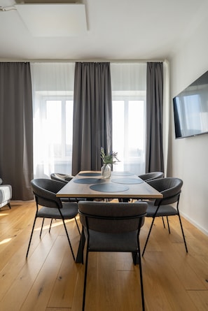 Un espace repas moderne avec une table en bois, des chaises à revêtement gris et un vase rempli de fleurs.