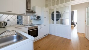 Una cucina moderna con mobili bianchi, una cappa in acciaio inossidabile, un forno a microonde e un forno integrato.