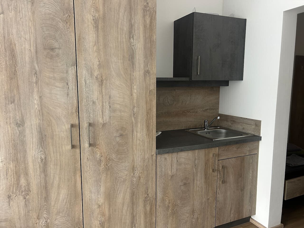 A kitchen with wooden cabinets, a black countertop, and a built-in sink.
