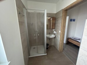 Ein Badezimmer mit Duschkabine, Waschbecken und einer hölzernen Sitzbank.
