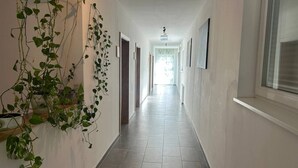 A long, narrow hallway with tiled flooring, white walls, and a ceiling light. - FarawayHomes Aparthotel Kremsmünster #13 (Kremsmünster)