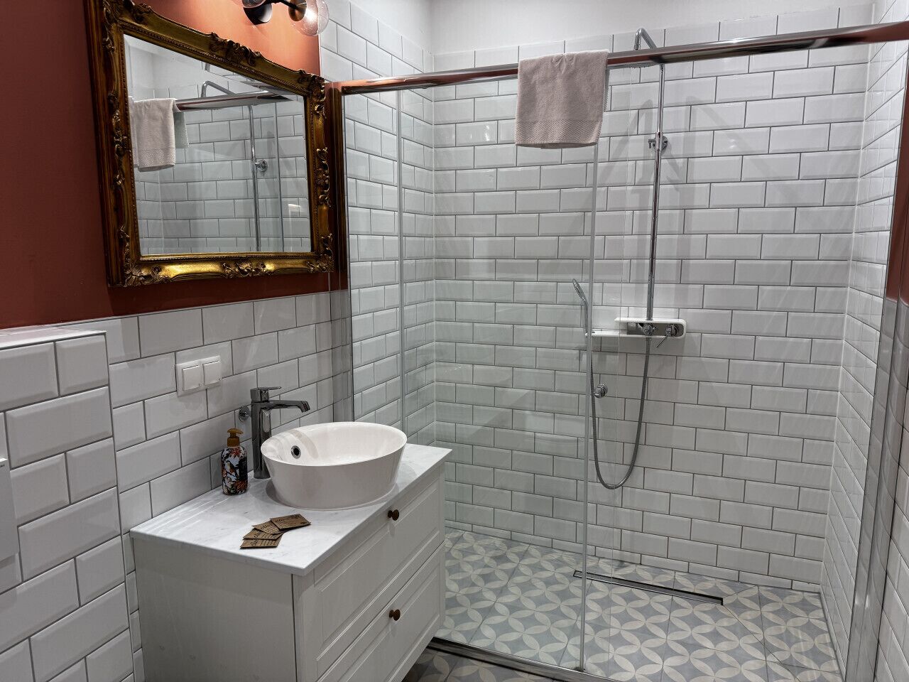 Een badkamer met een witte wastafel, een spiegel en een douche.