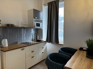Eine moderne Küche mit Holzausziehtisch, weißen Schränken, einer Mikrowelle und einem Fenster mit Vorhängen.