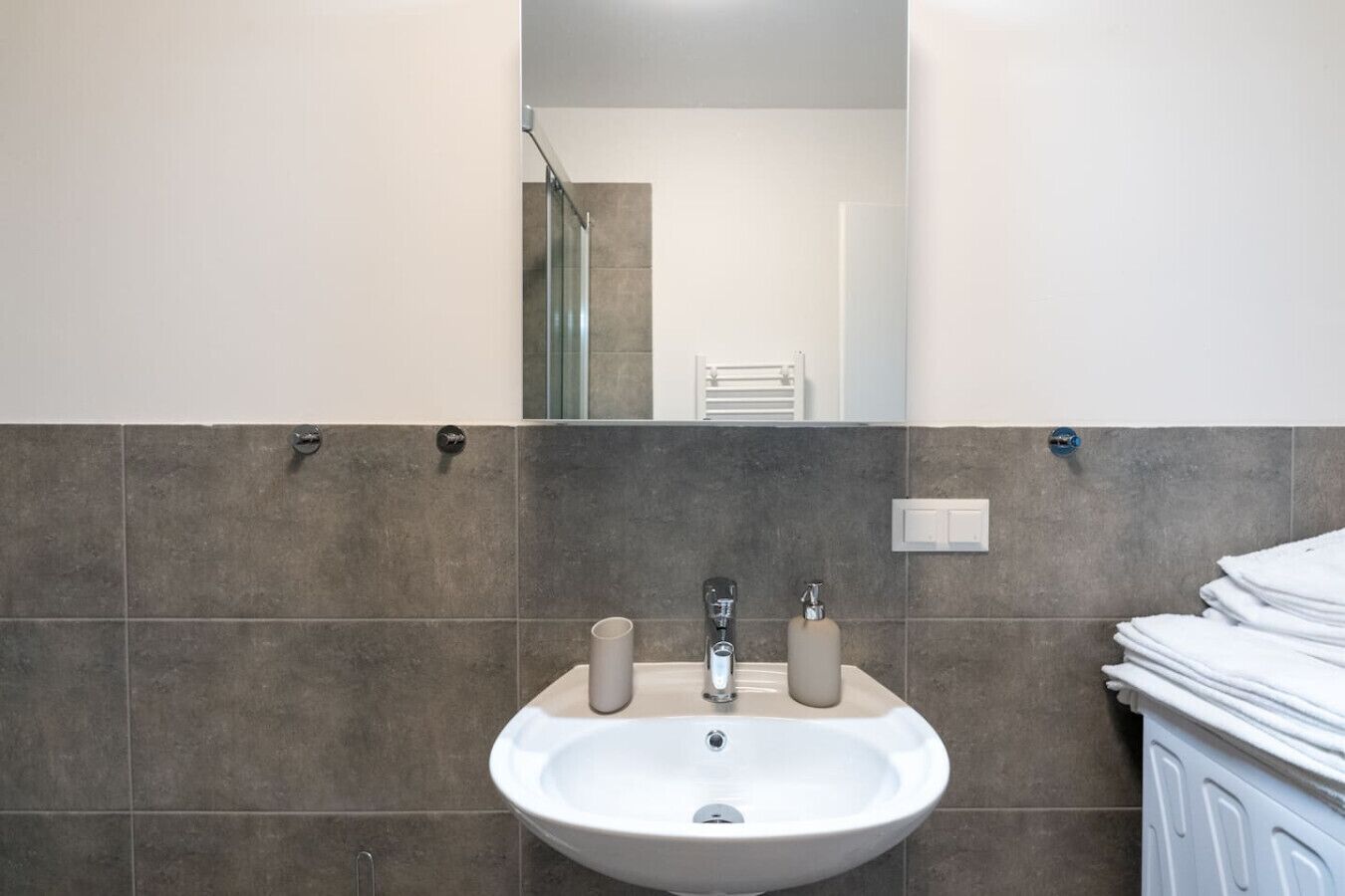 A bathroom with a sink, two faucets, a mirror, and a towel rack.