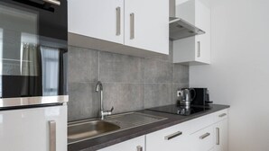 A modern kitchen with a stainless steel sink, a kettle, and a coffee maker.