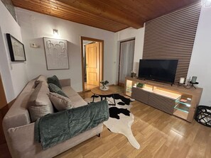 Ein Wohnzimmer mit einer Couch, einem Couchtisch, einem Fernseher und einem Holzschrank.