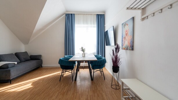Una sala de estar moderna con comedor, un sofá, una mesa y una planta en maceta.